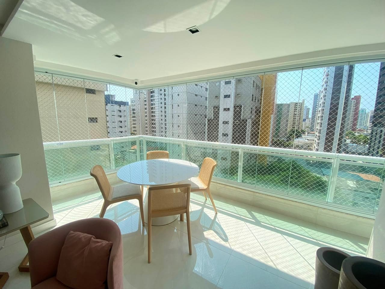 Cortina de vidro em varanda decorada com poltrona