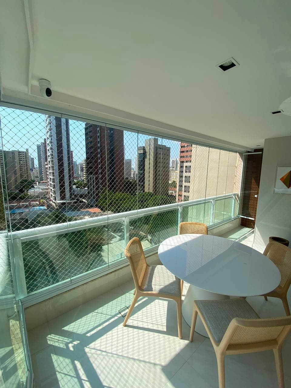 Varanda gourmet com cortina de vidro e vista da cidade