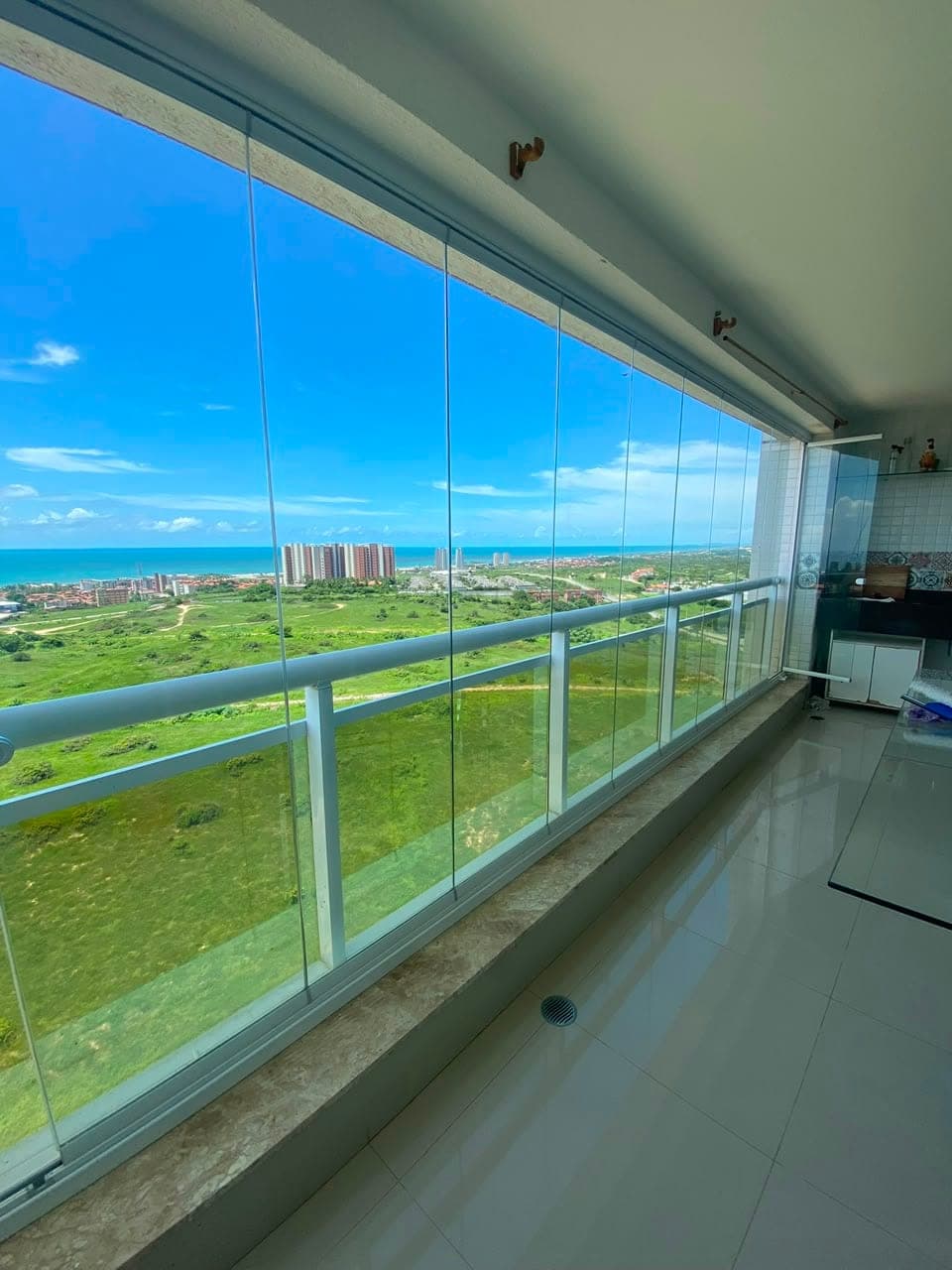 Varanda com cortina de vidro e vista para o mar em Fortaleza